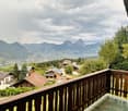 Balcony overlooking a scenic mountain landscape with houses and trees in the foreground.