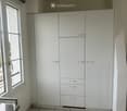Modern kitchen with white cabinets, marble tiled floor, and a large window providing natural light.