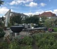Well-maintained garden with a patio area, outdoor dining set, fire pit, potted plants, and neatly arranged shrubs and flowers.