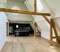 Modern kitchen with dark cabinets, stainless steel oven, and wooden beams in an open loft space.
