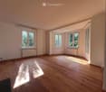 Empty room with wooden flooring, large windows, radiators, and natural light. No furniture or equipment present.