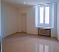Empty room with tiled floor, white walls, large window, radiator, and a small built-in shelf.