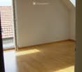 Empty room with wooden flooring, white walls, and a large window opening to a balcony. No furniture or equipment present.