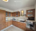 Modern kitchen with wooden cabinets, stainless steel appliances, and a marble countertop.
