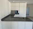 Modern kitchen with white cabinets, dark granite countertop, built-in oven, and sink with faucet.