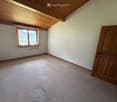 Empty room with wooden door, window with metal bars, and carpeted floor.
