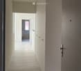 Modern hallway with light-colored walls, tiled floor, built-in cabinets, and a single pendant light fixture.