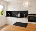 Modern kitchen with white cabinets, black countertops, and stainless steel appliances. Features a coffee maker, oven, sink, and various kitchen utensils.