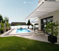 Well-maintained garden with a swimming pool, patio seating, and lush greenery.