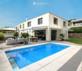Modern outdoor area with a swimming pool, patio furniture, and a covered seating area adjacent to a contemporary house.