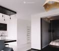 Modern open-plan living space with a kitchen area, dining table, and a separate bedroom area with a bed and lamp.