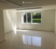 Empty room with white walls, tiled floor, and large window with view of greenery outside.