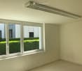 Empty room with large windows, white walls, and tiled floor. No furniture or equipment present.