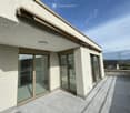 Balcony with large glass sliding doors, tiled floor, and a retractable awning on the roof.