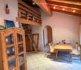 A cozy, wooden-furnished room with a dining table, chairs, a wooden cabinet, and a small loft area with a ladder.