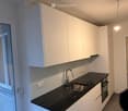 Modern kitchen with white cabinets, black countertop, and stainless steel sink.