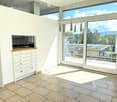 Bright, modern room with large windows offering a scenic view, a white cabinet with drawers, and pendant lights hanging from the ceiling.