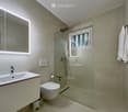 Modern bathroom with a sink, toilet, shower, and a large mirror. Features a towel rack, radiator, and a window providing natural light.