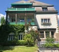 2 story house, white walls, green trim, balcony, garden, red flowers, green plants