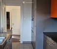 modern kitchen with gray cabinets, black countertops, stainless steel sink, two ovens, dishwasher, washing machine