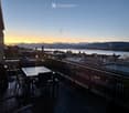 Balcony with a view of the city and water, featuring a table and chairs.