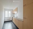 Modern kitchen with light wooden cabinets, granite countertop, stainless steel sink and faucet, black tiled floor, and a window with a view.