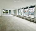Empty room with large windows, light-colored carpeted floor, white walls, and a modern ceiling design.