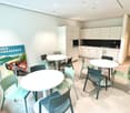 Bright, modern room with white cabinets, a sink, and three round tables surrounded by colorful chairs.