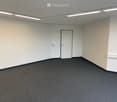 Empty room with white walls, black carpet, and a single white door.