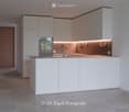 Modern kitchen with white cabinets, a central island, and built-in appliances including an oven and sink.