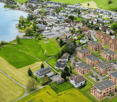 Aerial view of a residential area with multiple buildings, green spaces, and a lake in the background.