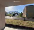 Balcony overlooking a landscaped outdoor area with benches, a paved walkway, and distant mountains.