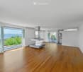 Bright, open living space with wooden flooring, large glass doors leading to a balcony with scenic views, a modern range hood, and a small table.
