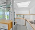 Modern kitchen with white cabinets, wooden countertops, a central island, and a large window offering a scenic view.