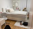 bedroom with a bed, chair, desk, lamp, mirror, toys, and a backpack