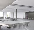 Modern office space with grey tables, chairs, and a potted plant in the corner.