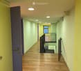 Bright hallway with wooden flooring, recessed ceiling lights, and a staircase leading to an upper level.