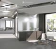 Modern, minimalist office space with a reception area, glass walls, sleek furniture, and a coffee machine on the counter.