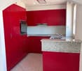 Modern kitchen with red cabinets, granite countertop, stainless steel oven, and sink.