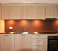 Modern kitchen with light wood cabinets, stainless steel sink, faucet, and built-in oven.