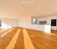 Modern, minimalist kitchen with white cabinets, a central island, and a large window offering a scenic view.