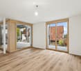 Empty room with wooden flooring, white walls, and large sliding glass doors leading to an outdoor area.