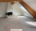 Empty attic room with exposed wooden beams, skylight window, fireplace with bench, and carpeted floor.