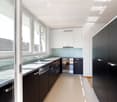 Modern kitchen with white and dark cabinets, granite countertops, stainless steel appliances, and large windows offering a view of the roof.