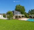 Well-maintained garden with a swimming pool, patio, outdoor furniture, and several potted plants.