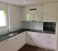 Modern kitchen with white cabinets, black countertops, stainless steel sink and faucet, and built-in oven.