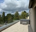 Modern balcony with tiled floor, glass railing, hot tub, and bench.