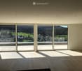 Empty room with large sliding glass doors offering a scenic view of a valley and town below. The room features wooden flooring and recessed ceiling lighting.