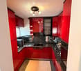modern kitchen, red cabinets, black countertops, white appliances, tile flooring, sink, faucet, stovetop, microwave, dishwasher, toaster, coffee maker, and lamps