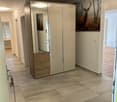 Modern hallway with tiled floor, large mirrored wardrobe, artwork of a deer, and recessed lighting.